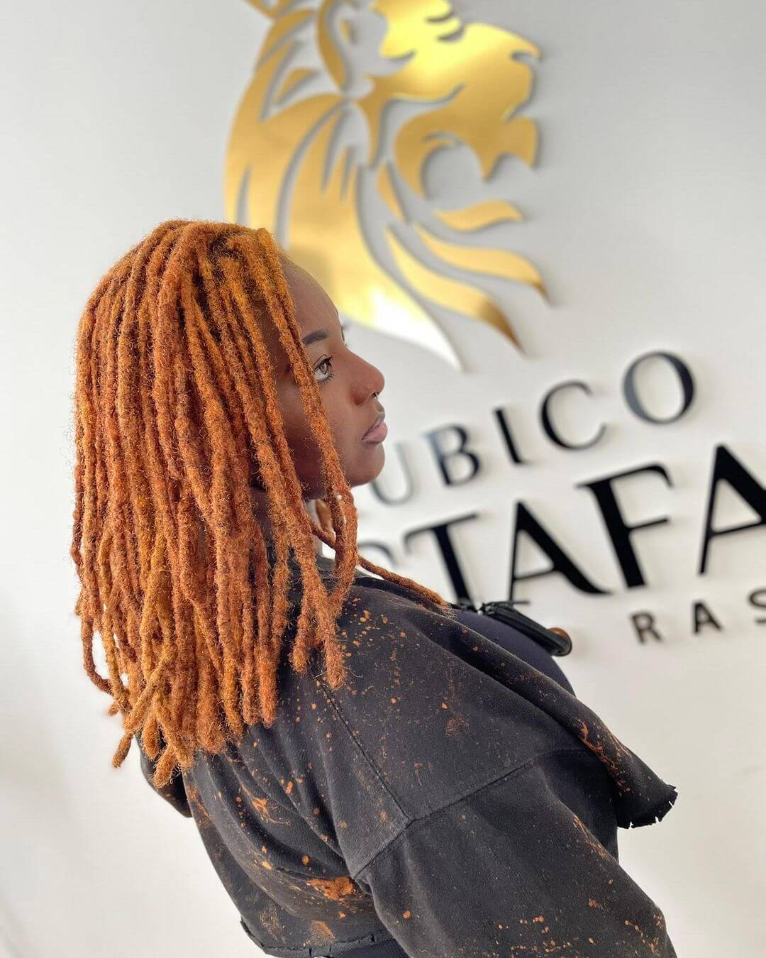 Shoulder-length dreadlocks glowing in a radiant copper hue.