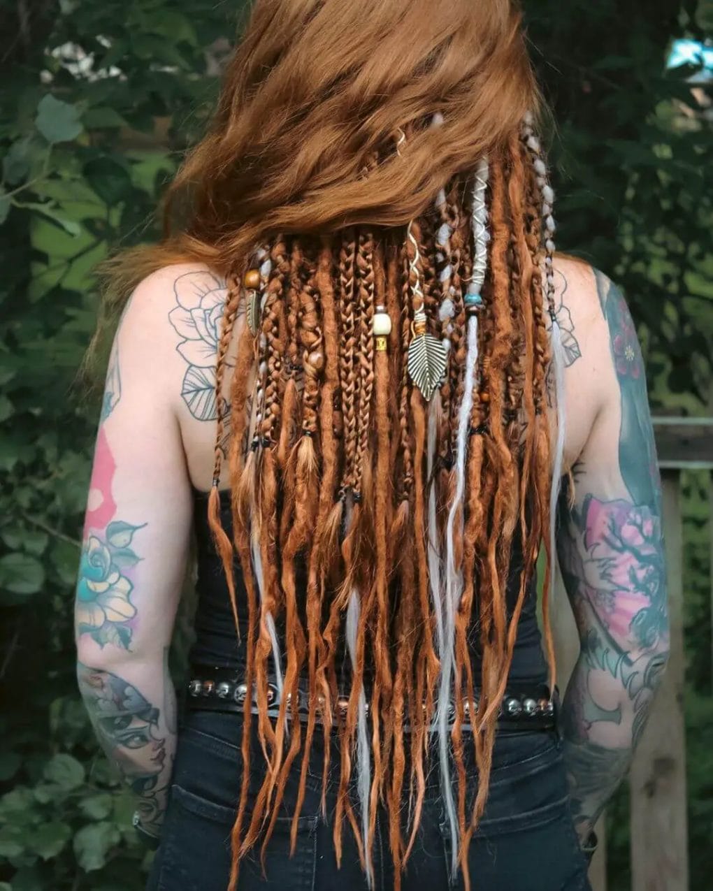 Fiery red dreadlocks styled in a peek-a-boo manner and adorned with charms, beads, and threads.