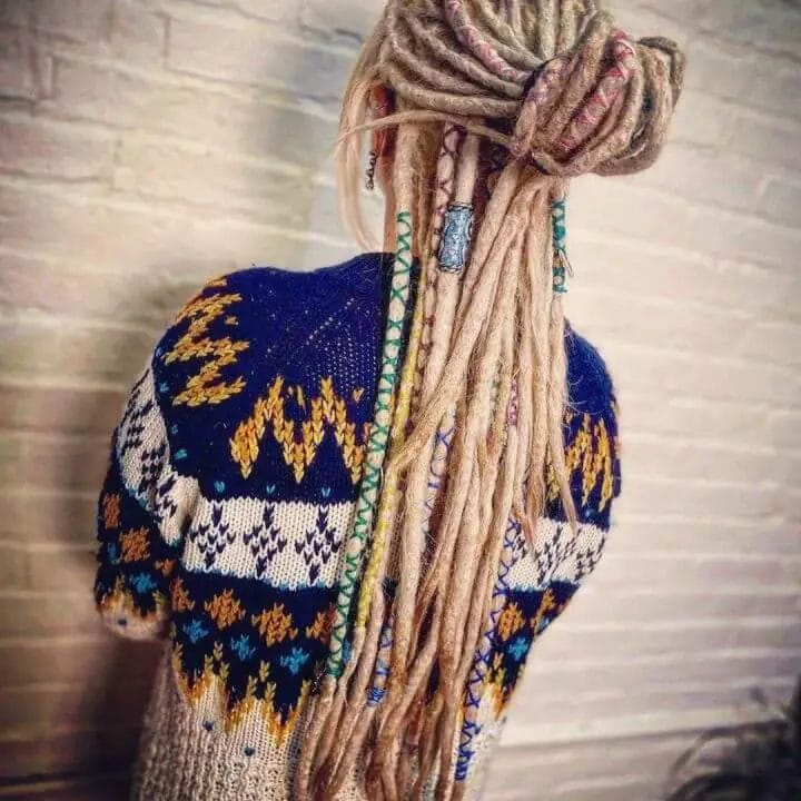 Elevated blonde dreadlock updo adorned with vibrant threads and beads.