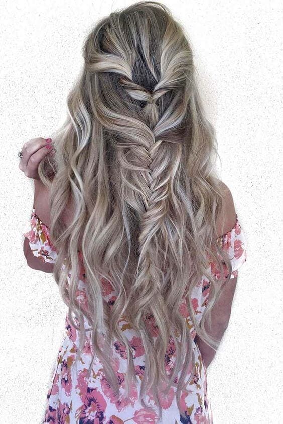 Half up half down bun featuring loose waves and a textured braid, perfect for casual events or prom, exuding an elegant vibe.