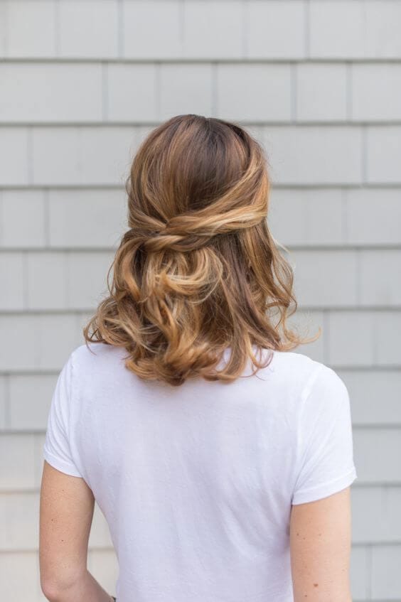 Loose curls styled in a half-up, half-down bun, showcasing warm blonde and light brown tones for a relaxed, elegant look.
