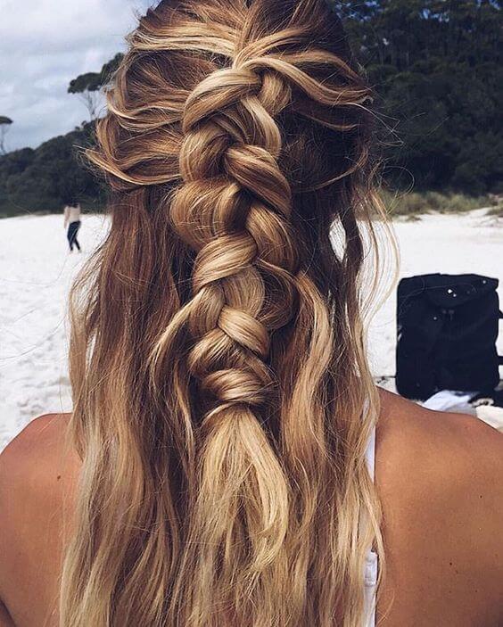 Half up half down bun with loose strands framing the face, featuring a smooth texture and sun-kissed blonde hue, perfect for formal occasions.