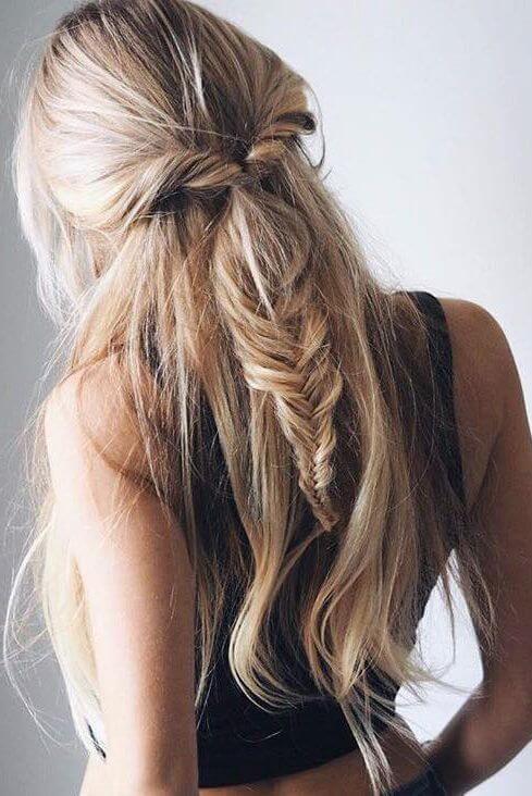 Half up half down bun featuring a relaxed fishtail braid with loose strands framing the face, perfect for casual or semi-formal events.