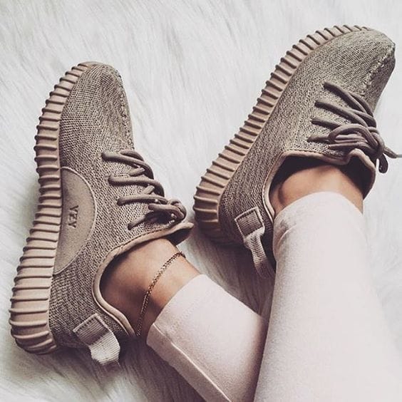 Light beige knitted sneakers with rounded toes and thick ribbed soles, styled with double-knotted laces, perfect for casual wear.