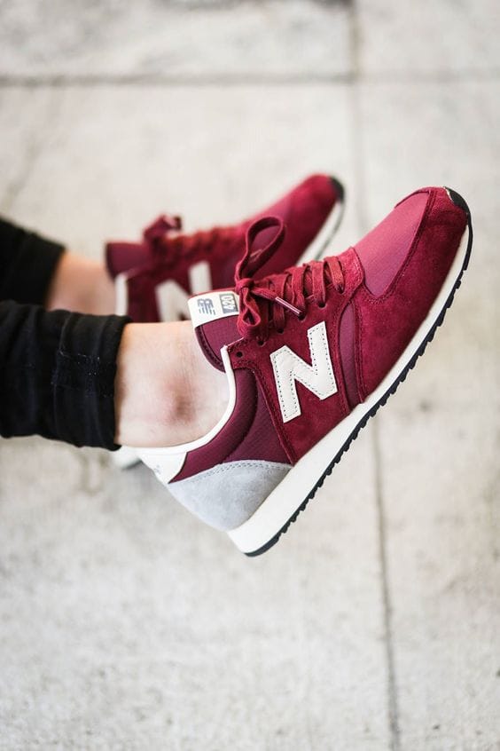 Maroon sneakers featuring suede and mesh materials, a white logo, and grey heel panel. Perfect for casual wear on a smooth surface.