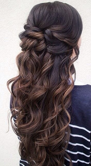 Loose, cascading curls styled in a half-up bun with dark and light brown tones, perfect for formal or casual occasions.