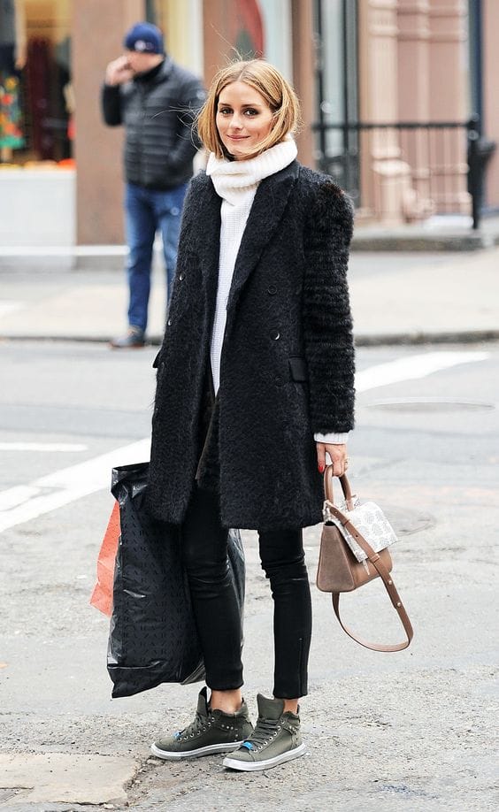Layered street style outfit featuring a black textured coat, white turtleneck, fitted black leather leggings, and olive green high-top sneakers.