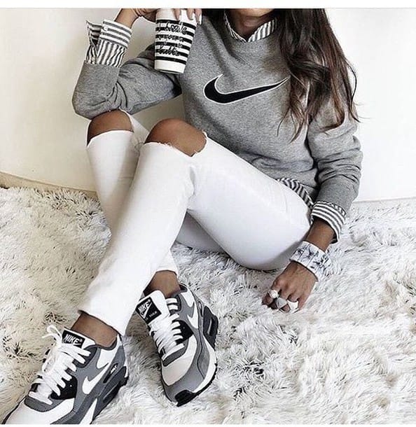 Casual outfit with a gray sweatshirt, white collared shirt, distressed white jeans, and gray-black athletic sneakers on an ivory rug.