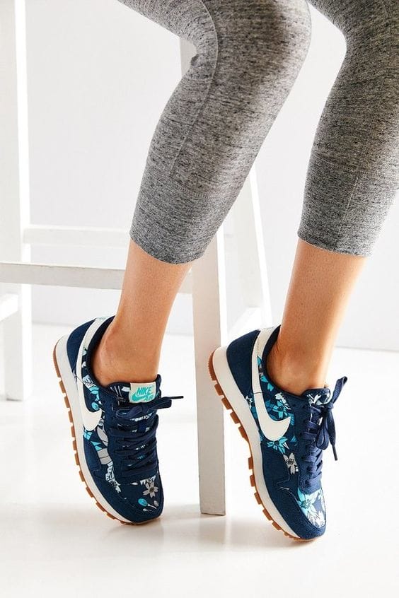 Navy blue sneakers with a floral pattern in white and aqua, featuring a round toe, cushioned collar, and laces for a secure fit.