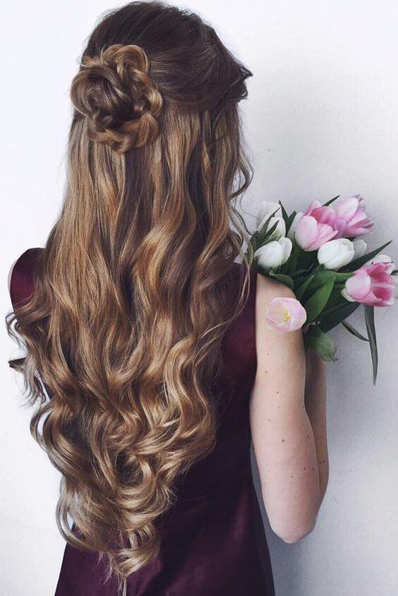 Long hair styled in a half up half down bun with soft waves cascading down, complemented by a bouquet of tulips for a spring aesthetic.