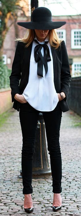 Oversized black felt hat paired with a structured black blazer and white blouse, set against a chic urban backdrop.