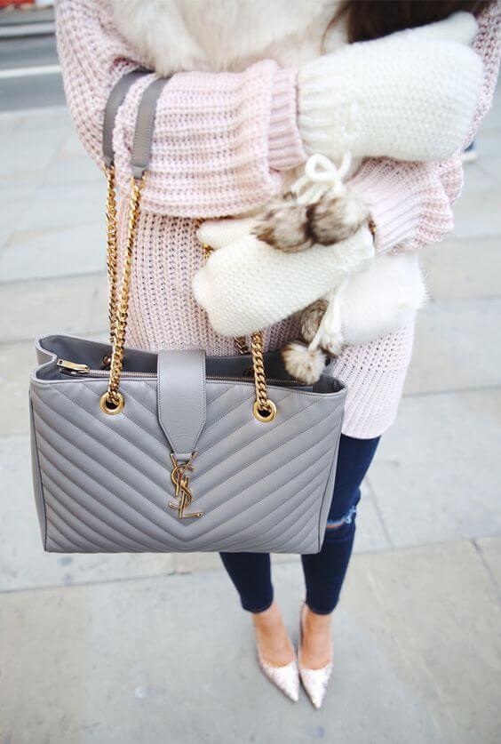 Medium-sized gray leather handbag with quilted design, gold-tone chain strap, and top zipper, styled for casual winter outfits.