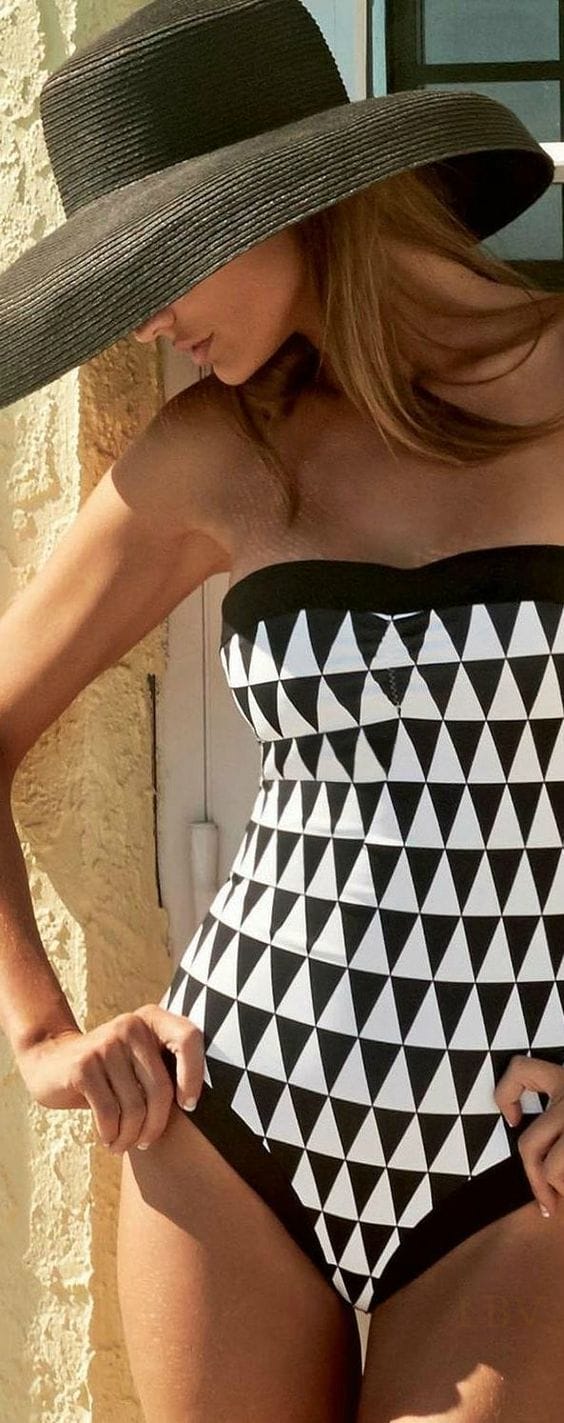 Wide-brimmed black straw sun hat paired with a sleek, strapless one-piece swimsuit, perfect for beachwear and sun protection.