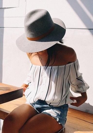 Loose, flowing hair complements a laid-back outfit, enhancing the relaxed vibe of a wide-brimmed straw sun hat in natural sunlight.