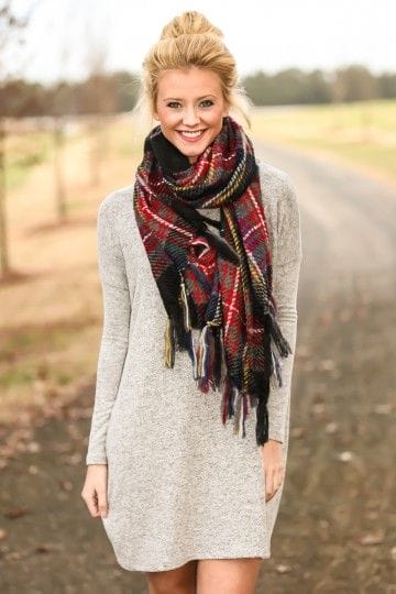 Multi-colored scarf with red, black, and yellow stripes, draped around the neck, complements a light gray long-sleeved dress, ideal for casual outings.