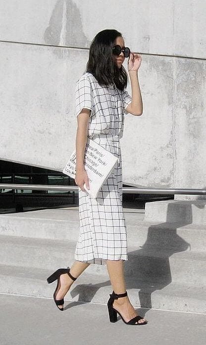 Sleek black and white outfit featuring an elegant fitted mini skirt, complemented by oversized black sunglasses for a chic urban look.