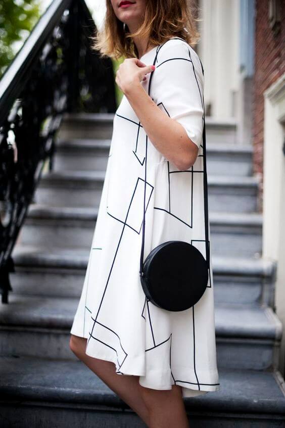 Elegant black and white skirt outfit featuring a geometric design, paired with a chic round crossbody bag, perfect for classy occasions.