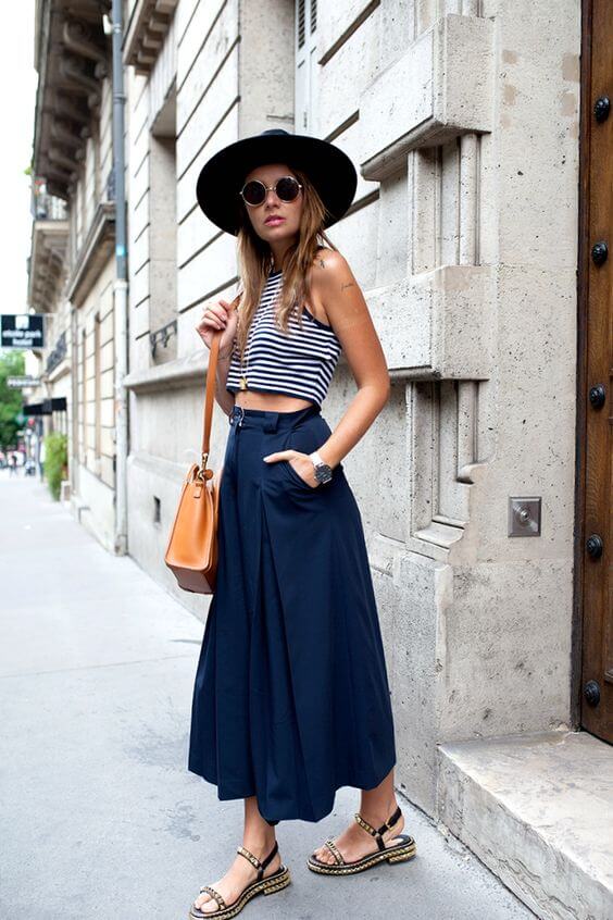 Striped crop top in navy and white, paired with high-waisted navy culottes, accessorized with a black hat and round sunglasses, perfect for summer outings.