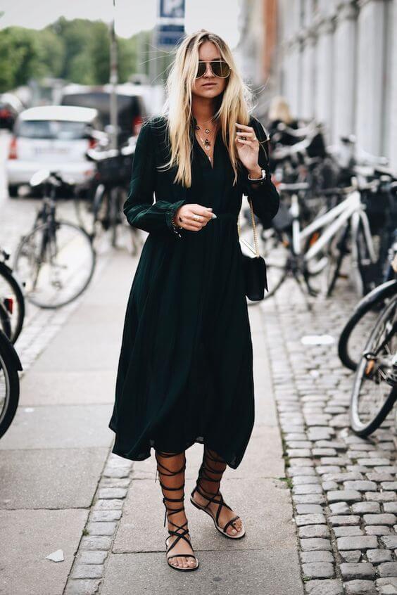 Chic summer outfit featuring a flowing green dress and strappy sandals, complemented by layered necklaces and oversized sunglasses.