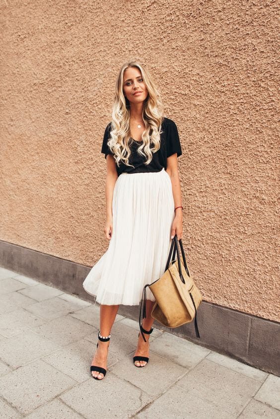 Elegant outfit featuring a black short-sleeved top and a flowy white pleated midi skirt, perfect for casual outings.