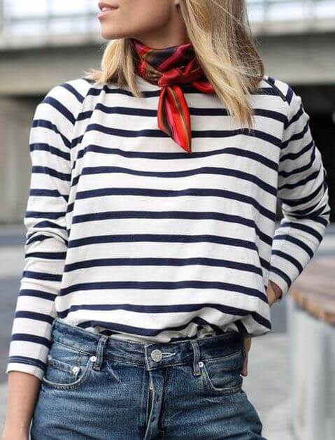 Smooth, straight hairstyle with layers, paired with a navy and white striped shirt, high-waisted jeans, and a vibrant silk scarf.