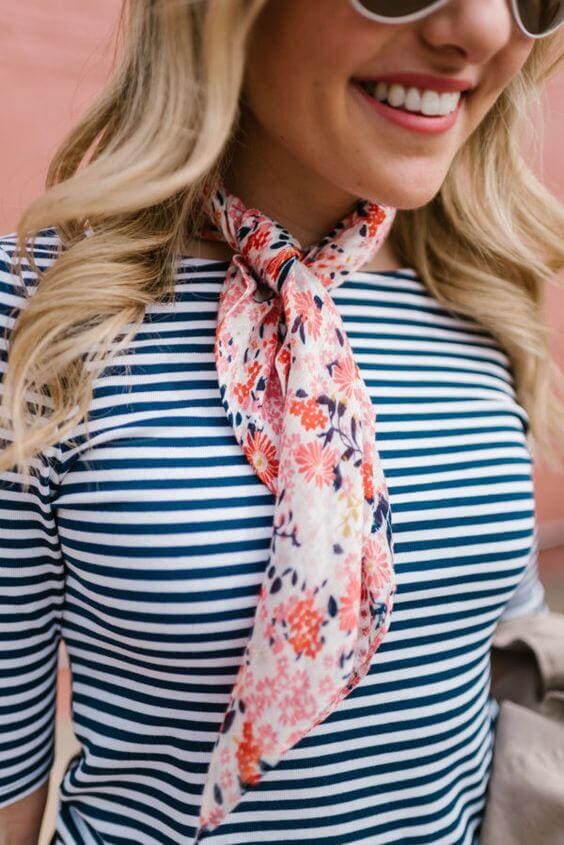 Floral scarf in pink and navy tied around the neck, layered over a fitted navy and white striped shirt, perfect for summer style.