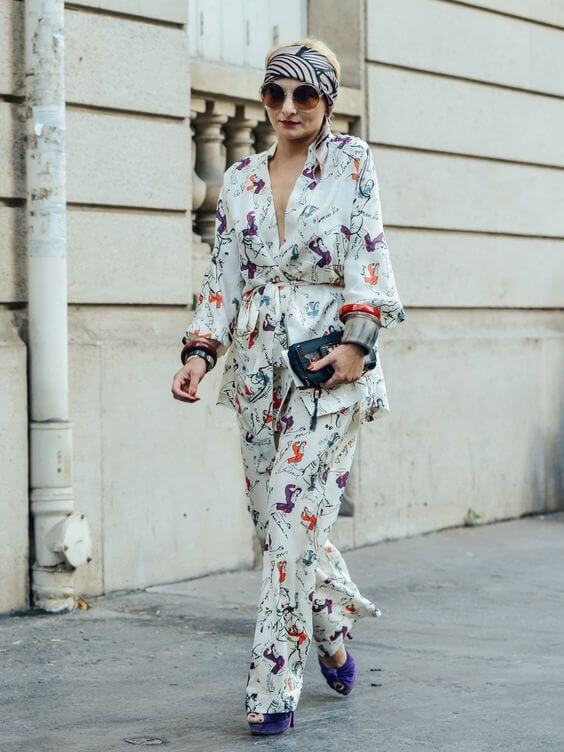 Outfit features a flowing, patterned silk scarf paired with a chic long-sleeved top and wide-leg pants, perfect for summer styling.