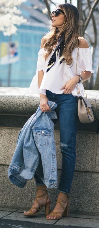 Long, wavy hair complements a chic outfit featuring an off-the-shoulder white top and distressed jeans, embodying effortless summer scarf style.