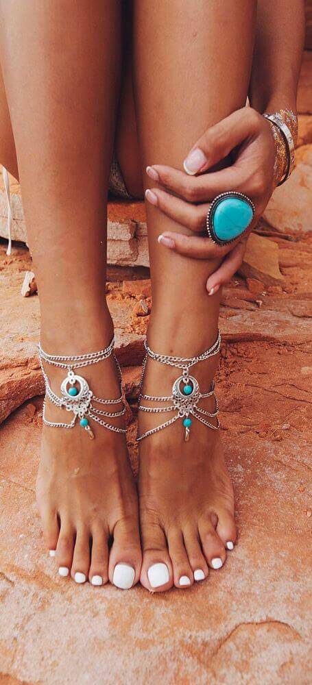 Intricate ankle jewelry featuring silver chains and turquoise stones, enhancing the feet's beauty with a vibrant, boho flair.