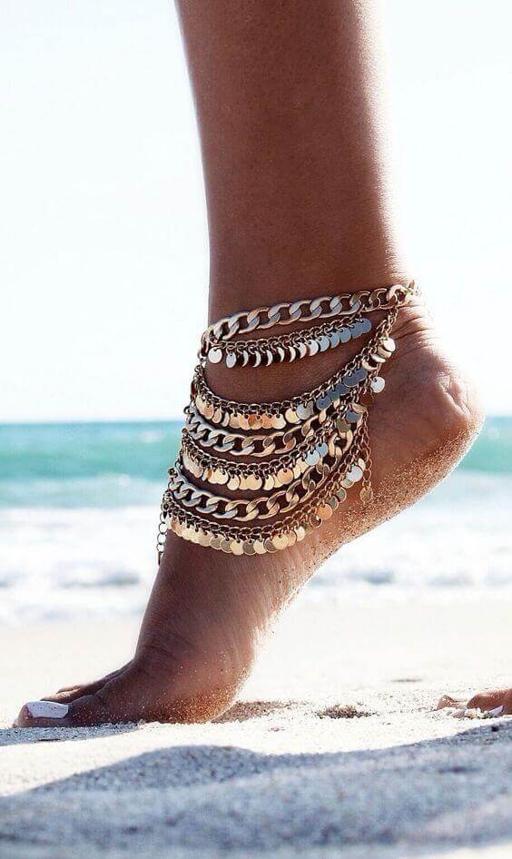 Bohemian-style anklet featuring layered gold chains and circular charms, perfect for summer outfits and beach settings.