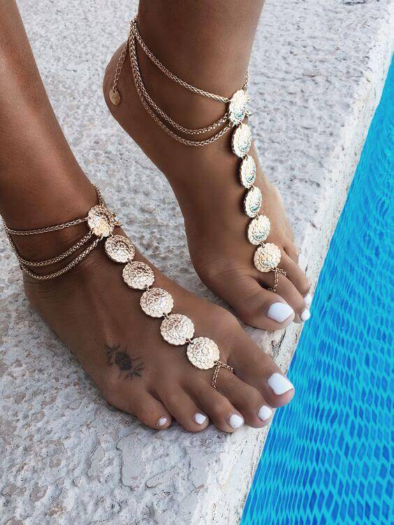 Ornate ankle bracelet with metal chains and circular pendants, enhancing foot beauty for summer vibes and beach settings.