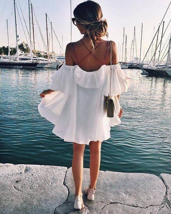 Flowy, off-shoulder white sundress perfect for summer. Features ruffled neckline, mid-thigh length, ideal for beachy outings.