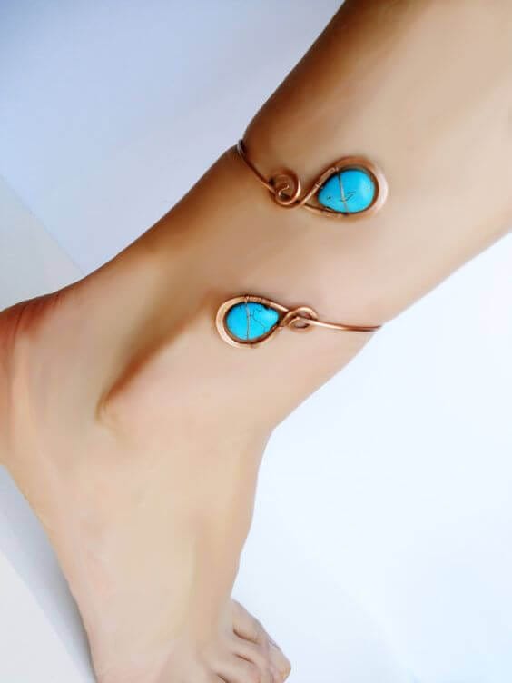 Turquoise teardrop stones adorn a delicate copper anklet, blending bohemian style with elegance, perfect for summer wear.