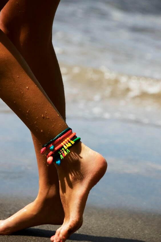Anklet with colorful beads and elastic bands, featuring vibrant red, blue, yellow, and pink layers, perfect for summer beach wear.