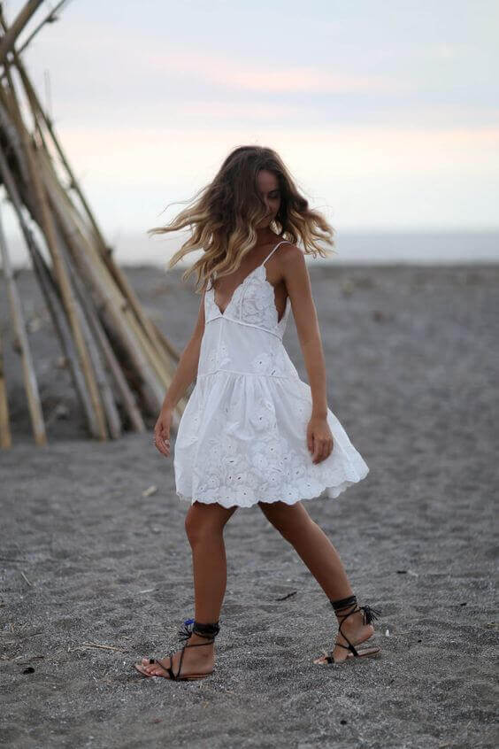 Wavy hair complements a flowing white sundress, enhancing a relaxed summer vibe perfect for beach outings.