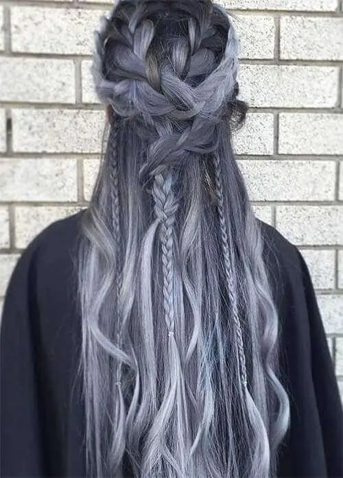 A woman's hair with dark roots fading into silver-gray highlights, intricately braided from the crown into a half-up, half-down style.