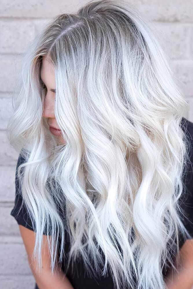 A woman's cascading mane featuring icy silver roots melting into pristine platinum waves, with soft, seamless layers for depth and volume.
