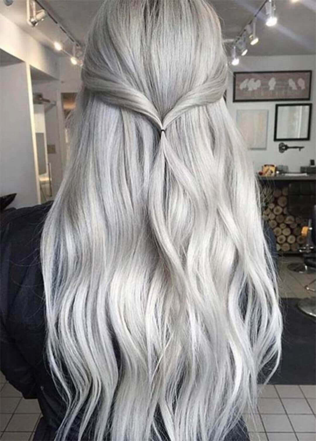 A woman's long, flowing mane featuring icy silver and subtle gray highlights, styled with a simple half-up twist, cascading in loose waves.