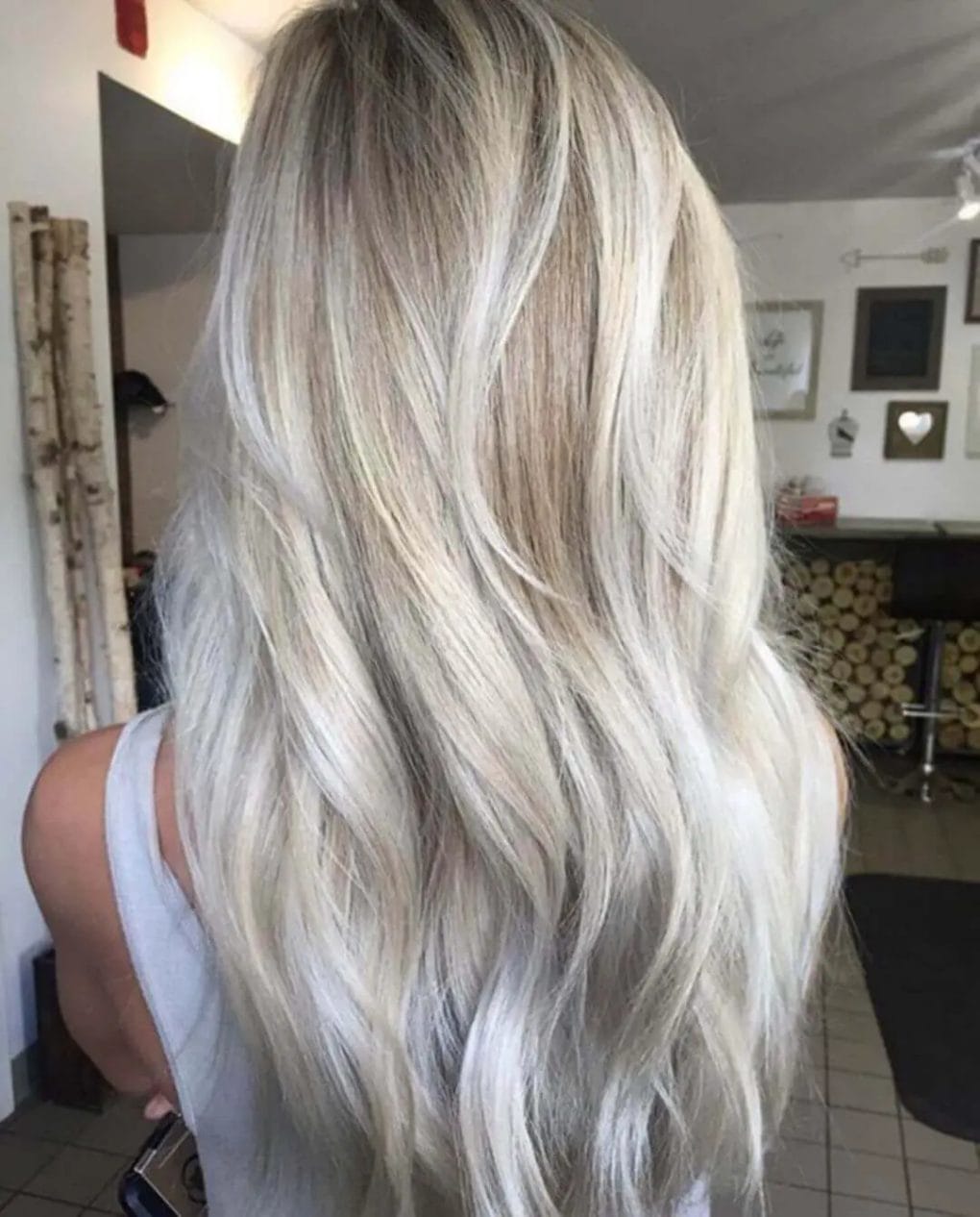 A woman's hairstyle featuring a harmonious blend of platinum and ashy gray highlights, with effortlessly flowing cascading layers softly tousled for natural volume and movement.