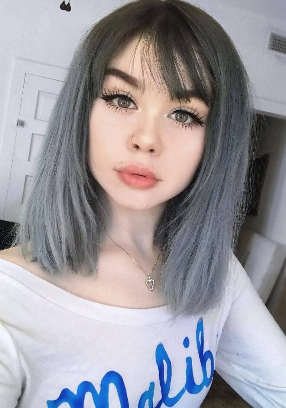 Chic bob with slate blue and gray highlights, straight-cut bangs, and sleek layered style for a fresh and modern classic-edgy look.