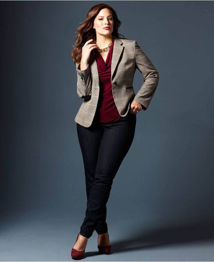 Tailored plaid blazer, burgundy top, fitted dark jeans, and stylish burgundy heels create a sophisticated plus size office outfit.