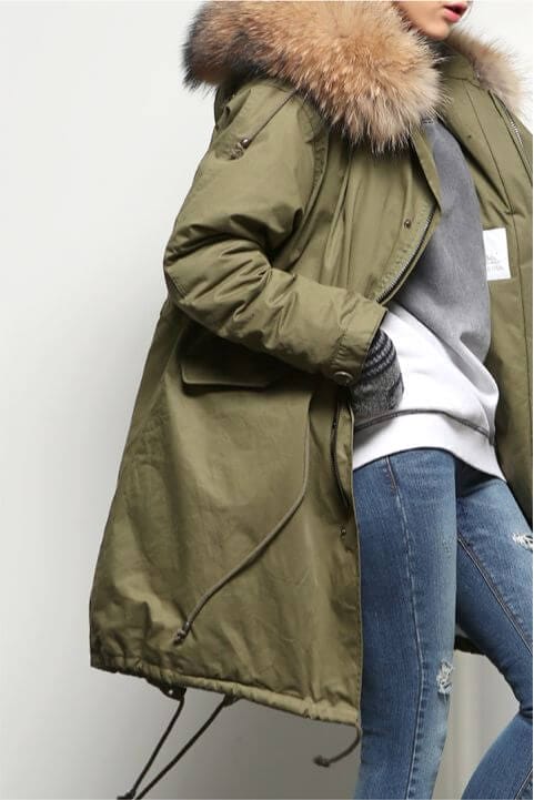Olive green parka jacket with faux fur hood, layered over a gray sweatshirt and distressed jeans, perfect for cold weather outings.