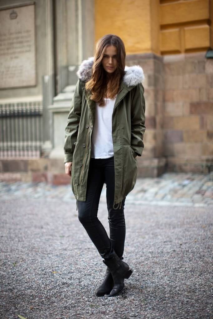 Casual parka jacket outfit in olive green with faux fur trim, paired with a white t-shirt and fitted black jeans, ideal for cool weather.