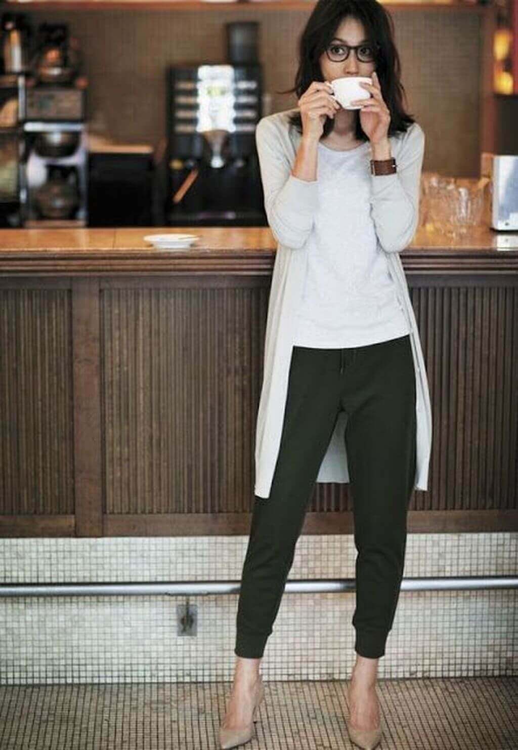Casual chic outfit with a light gray cardigan, dark green jogger-style pants, and nude heels, set in a relaxed cafe atmosphere.