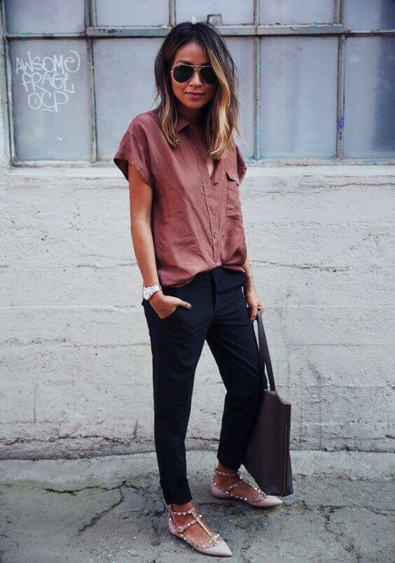 Long, layered brunette hair with highlights complements a rust short-sleeve blouse and black tailored pants, perfect for casual office attire.