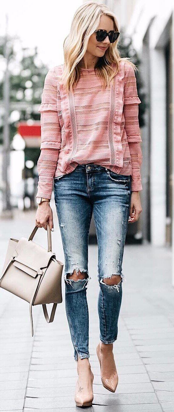 Light pink textured top paired with distressed blue skinny jeans and nude high-heeled shoes, complemented by a structured beige handbag.