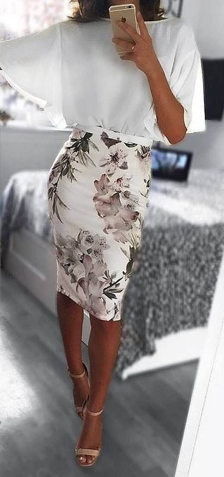 Stylish white top with wide sleeves and a fitted pencil skirt featuring floral patterns in soft pinks and greens, paired with strappy heels.