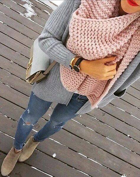 Cozy oversized gray cardigan over a light top, blush pink scarf, distressed blue jeans, and taupe ankle boots on wooden decking.