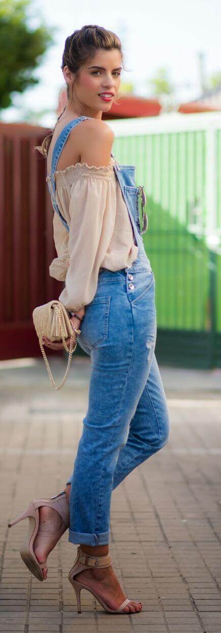 Light off-shoulder top in soft cotton paired with light-wash denim overalls. Finished with nude high-heeled sandals, set outdoors.