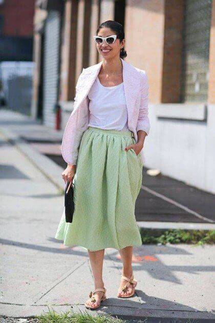 Casual pastel outfit featuring a light pink blazer over a white T-shirt and mint green skirt, paired with neutral sandals and oversized sunglasses.